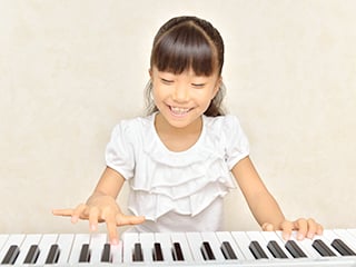 小学校低学年ほどの女の子がピアノを弾いている様子