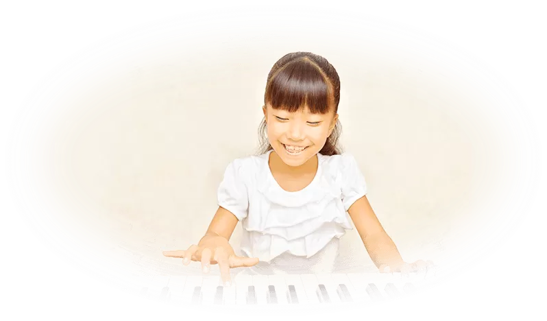 子どもが笑顔でピアノを弾いている写真